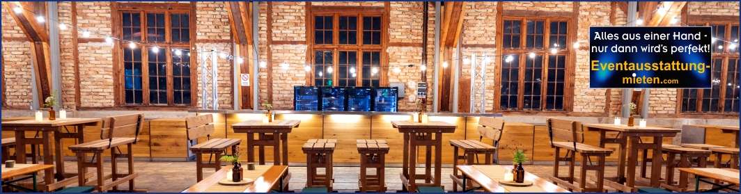 Hochtisch-Garnituren und rustikale Möbel für Buffet und Bar mit Lichterketten-Beleuchung in einer Eventlocation