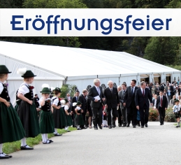 Großes weißes VIP-Zelte mit prominenten Gästen davor und jungen Trachtlerinnen, die Spalier stehen.
